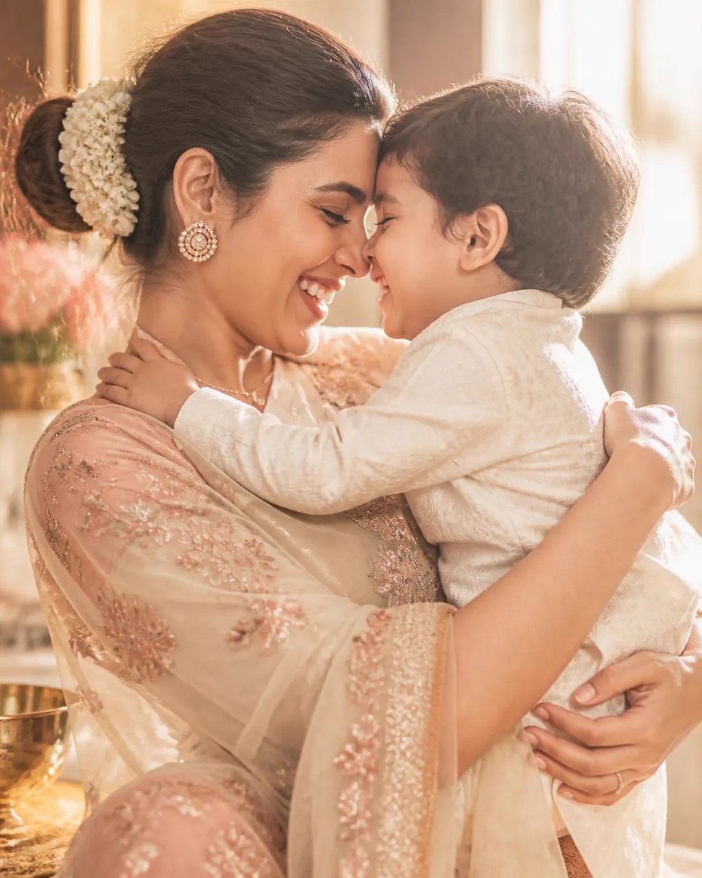 A radiant, happy mother hugging her child, foreheads touching
